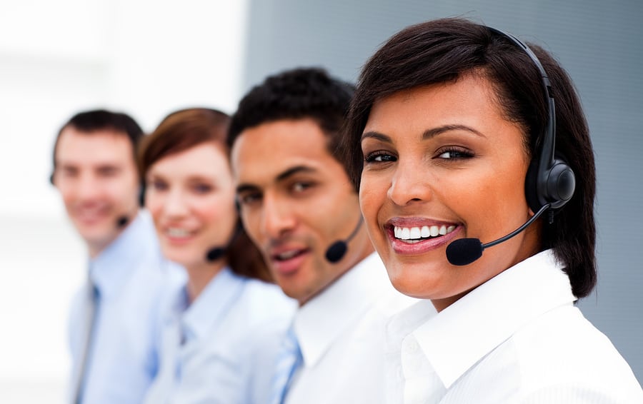 Ethnic businesswoman with headset on smiling at the camera in a call center
